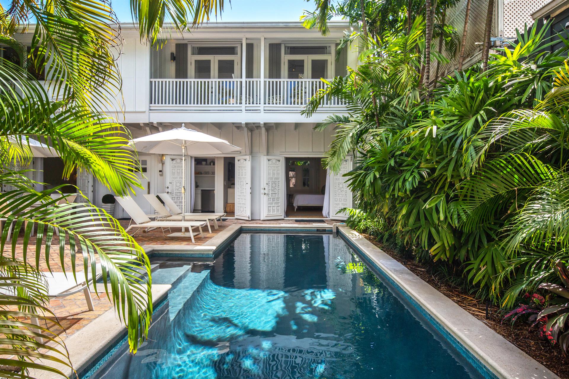 Elevated view of Cloud 9 pool and white two-story cottage framed by tropical palms