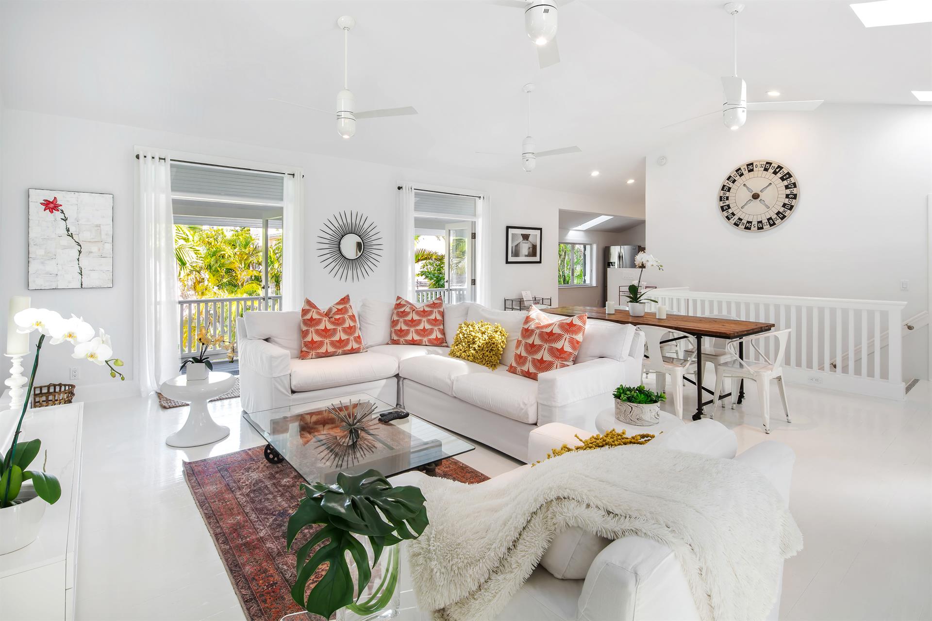 Open-concept living space with white sectional sofa, coral pillows, skylights, and natural light flooding the room