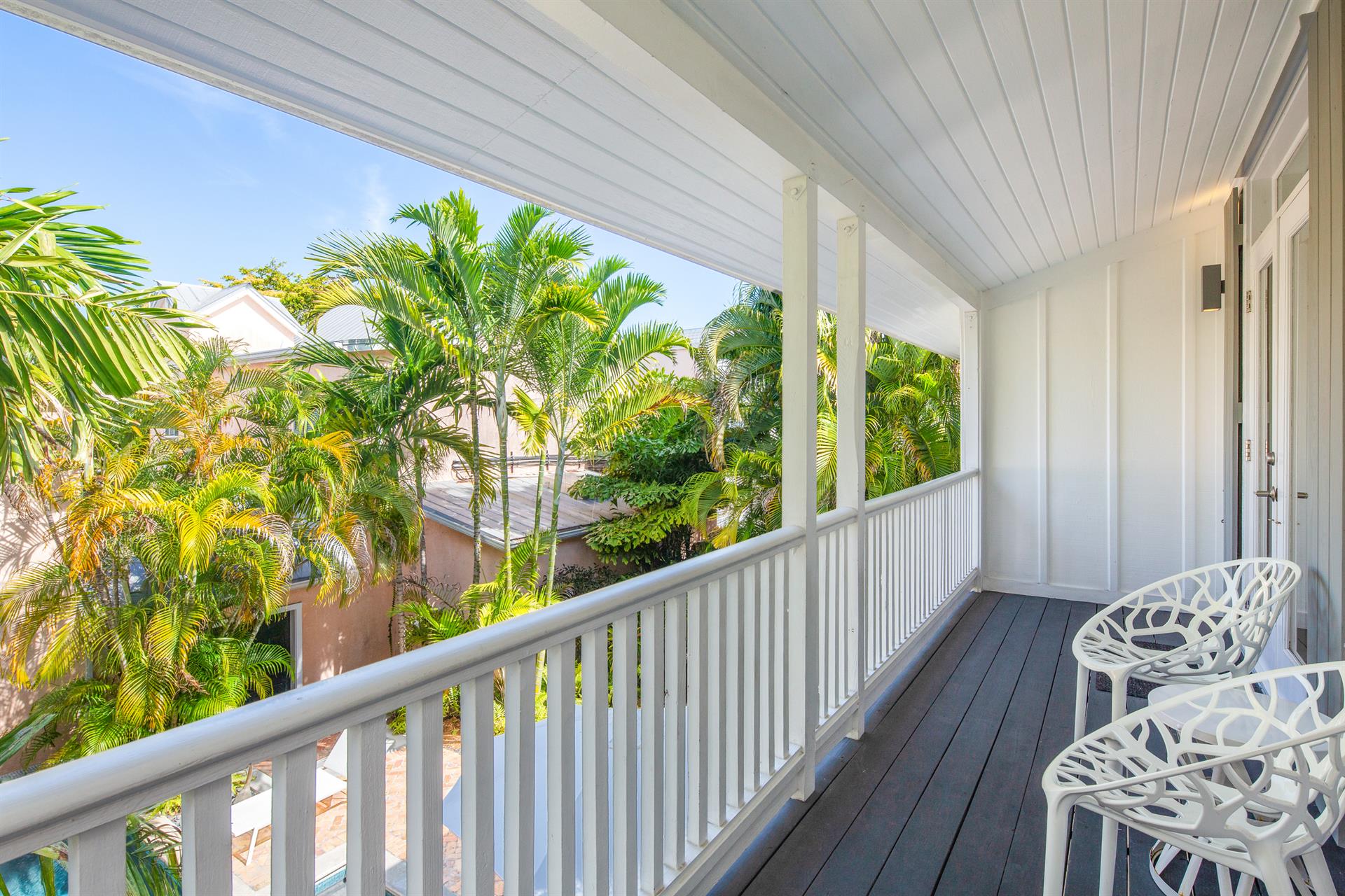 Upper-level balcony porch with white railings overlooking tropical canopy