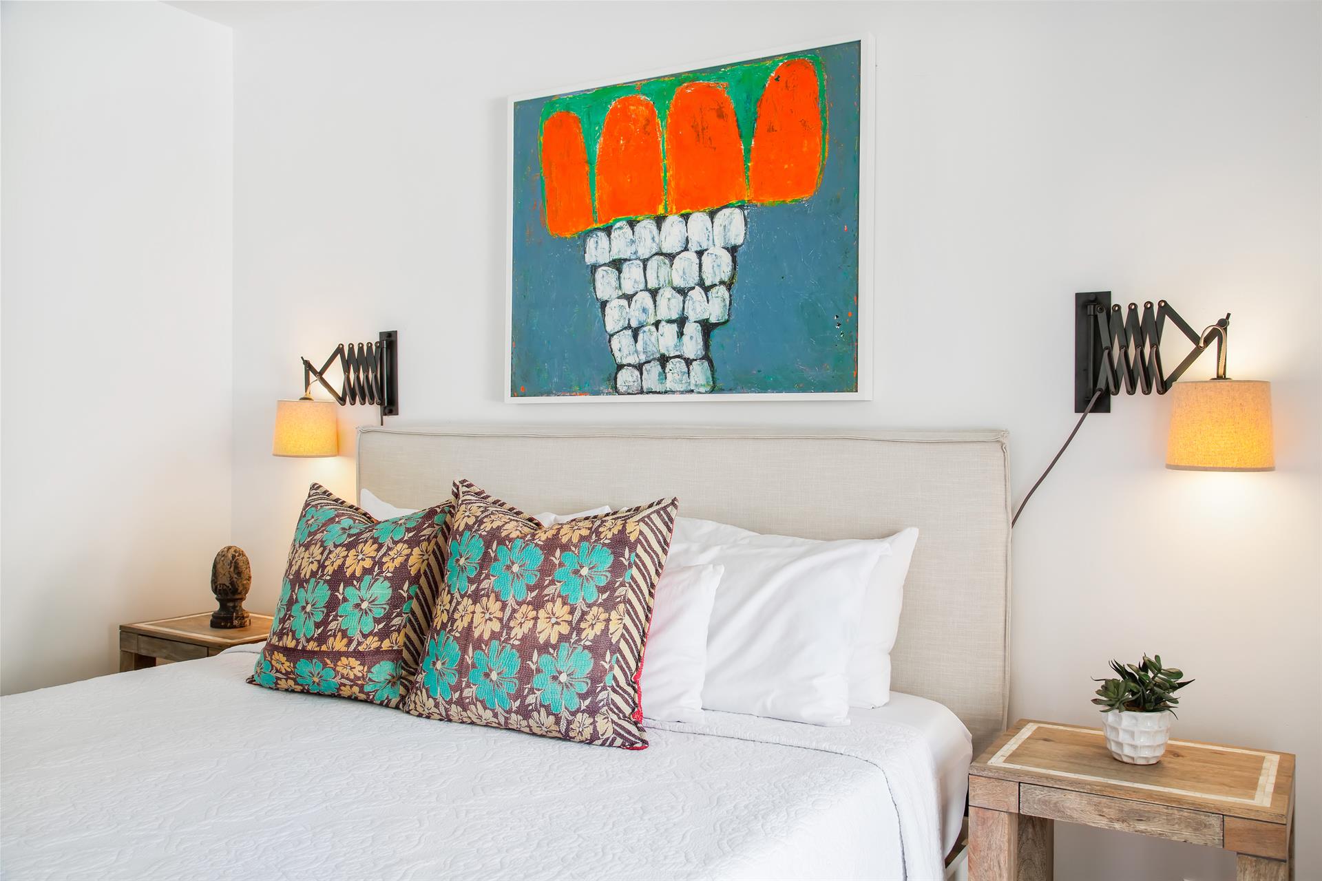 Master bedroom headboard detail with colorful art and patterned accent pillows