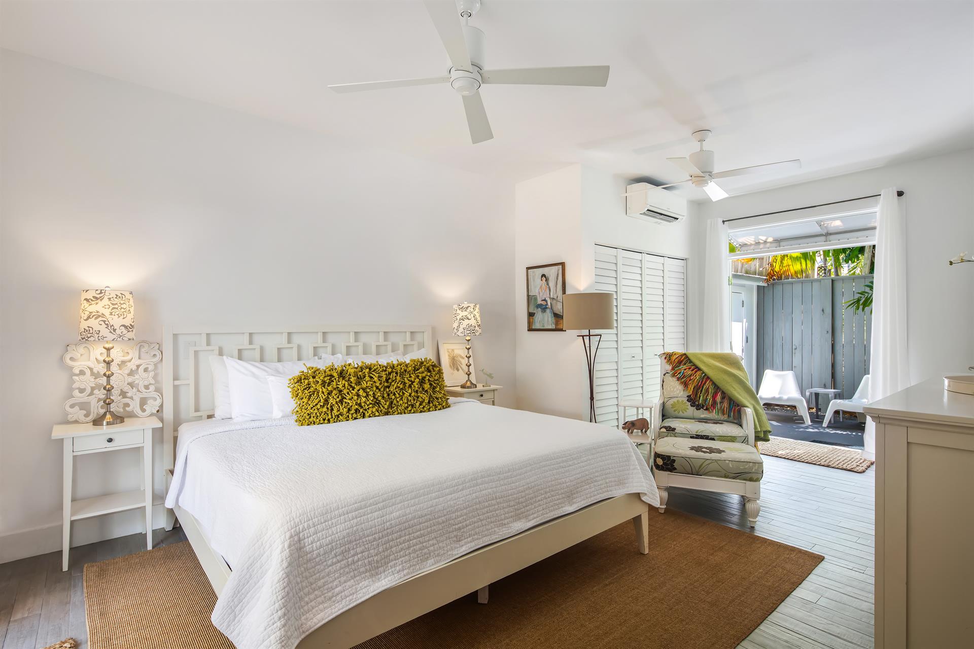 Second bedroom suite with white linens, louvered doors, and garden-green accents