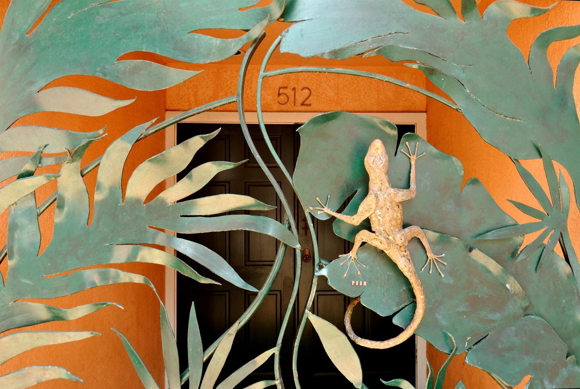 Signature gecko gate with custom iron tropical leaf and gecko metalwork bearing address 512