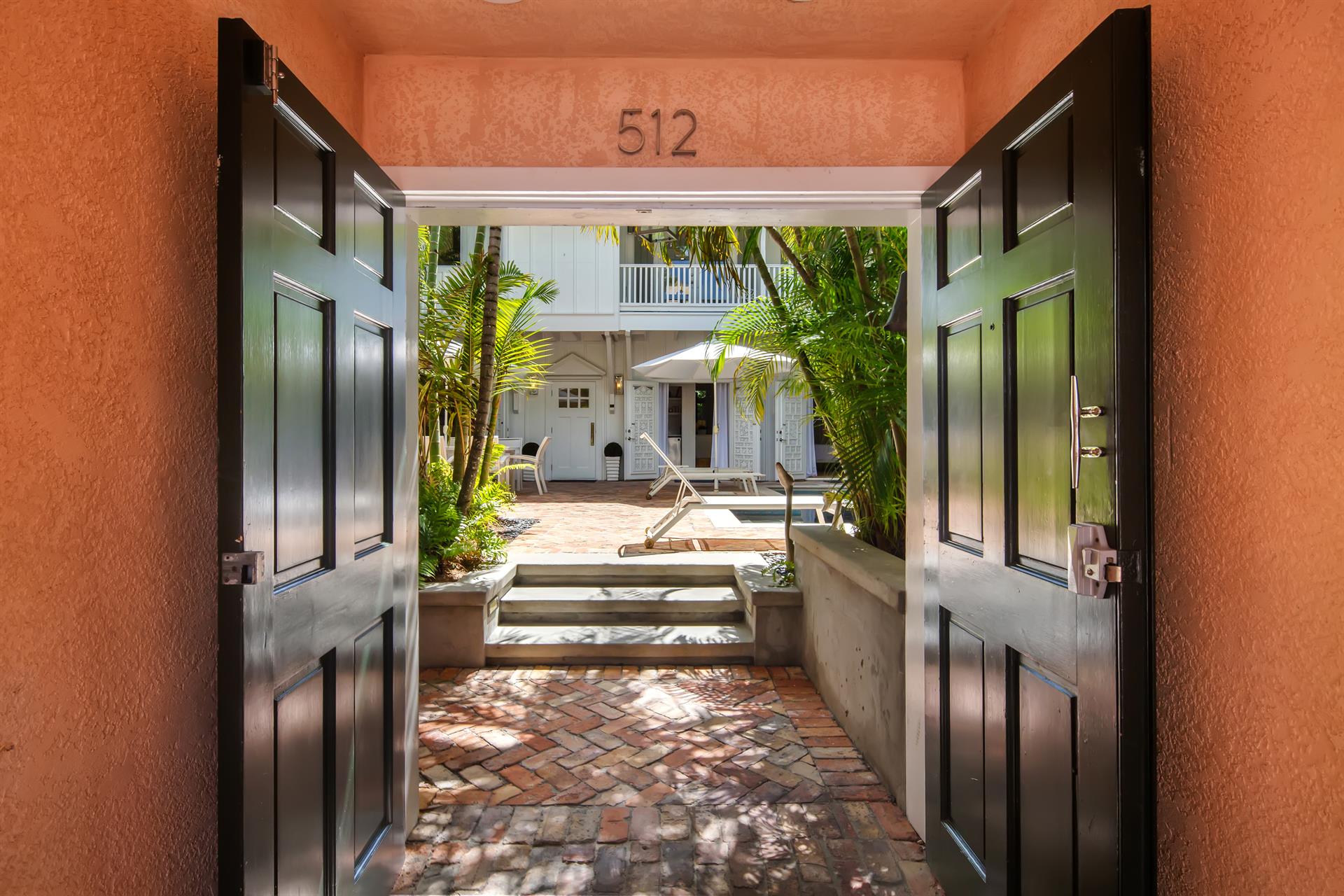 Open entrance doors revealing the pool courtyard beyond, framed by the terracotta facade